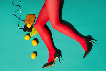 Womans legs in bright red tights and high heels with scattered lemons and purse