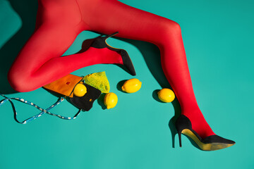 Womans legs in bright red tights and high heels with scattered lemons and purse
