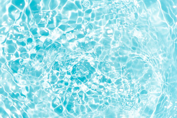 Blue water with ripples on the surface. Defocus blurred transparent blue colored clear calm water surface texture with splashes and bubbles. Water waves with shining pattern texture background.