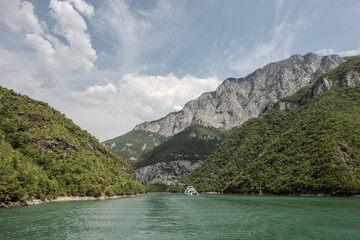 A boat is sailing on a lake surrounded by mountains covered in trees.