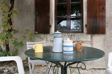 Traditional vintage coffee pot on table. Table and chairs in garden. France