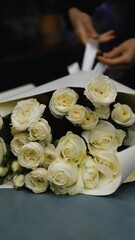 Beautiful white roses in a flower shop. Florist assembles a bouquet to order