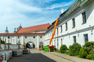 Fototapeta premium Historic buildings require careful renovation, building debris travels through an orange chute during roof repairs. Renovation of an old building. The roof is under construction.