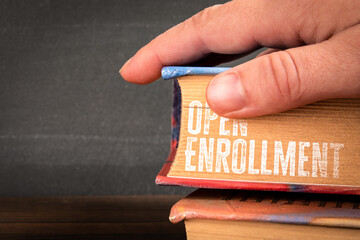 Hand holding book with Open Enrollment title text