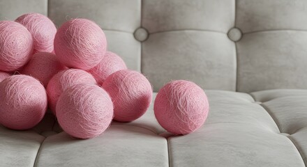 Pile of pink yarn balls on a tufted gray couch