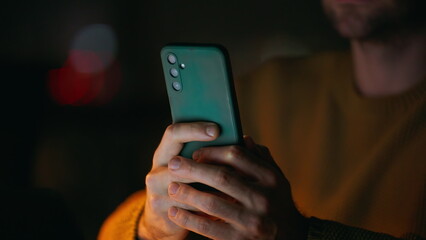 Startuper hands holding cellphone in night office closeup. Unrecognizable man