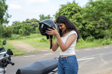 Strong independent Indian woman biker with her moped and helmet .