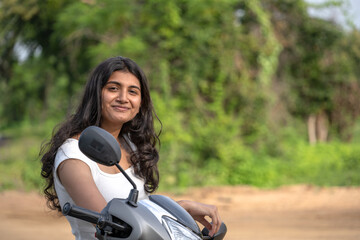 Fototapeta premium Strong independent Indian woman biker with her moped and helmet .