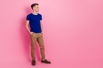 Portrait of a young man in blue t-shirt on pink background full body smiling confidently and casual style