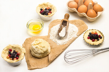 Flour and dough on paper. Baking cup with frozen berries and dough.