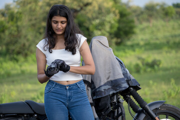Fototapeta premium Strong independent Indian woman biker: beautiful girl, stylish rider, motorcycle adventure, elegant jacket, confident posture, powerful machine, free spirit, road journey, fearless attitude.