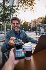 Businessman making contactless payment with smartphone at café - Smiling man in suit paying with...