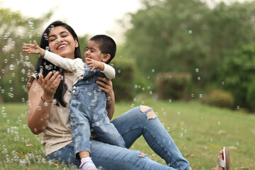 Fototapeta premium Mother And Child Enjoy Playing With Bubbles Outdoors