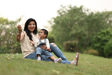 Fototapeta premium Joyful Mother And Child Playing With Bubbles Outside