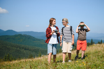 Fototapeta premium Children hiking in mountains using camera and binoculars