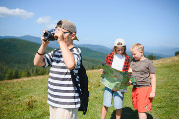 Children hiking in mountains taking photos and reading map