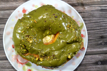 Pistachio cream paste topping and pieces of pistachios on a ring donut, a glazed, yeast raised,...