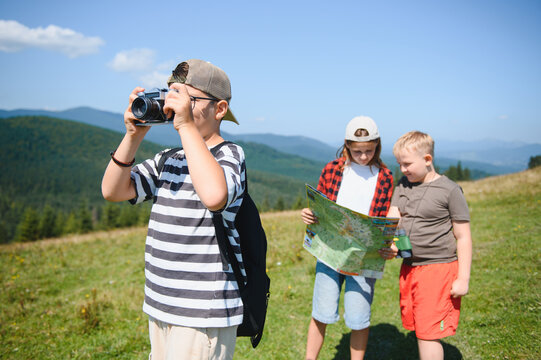 Children hiking in mountains taking photos and reading map