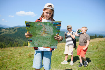 Children hiking in mountains using map and binoculars