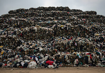 Obraz premium Massive Landfill Waste Heap of Discarded Clothes, Clothing, and Textile Trash. Environmental Pollution.