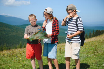 Children hiking in mountains consulting map and binoculars