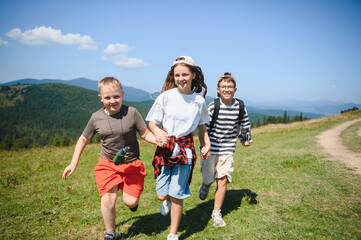 Happy children running on mountain meadow during summer vacation