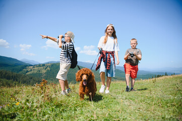 Children hiking in mountains with dog and binoculars