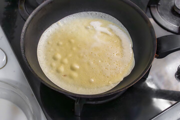 Pancakes are fried in a hot pan. Traditional homemade baking and cooking process.A series of home photos of the process of cooking pancakes in the kitchen. The pictures show different stages of the
