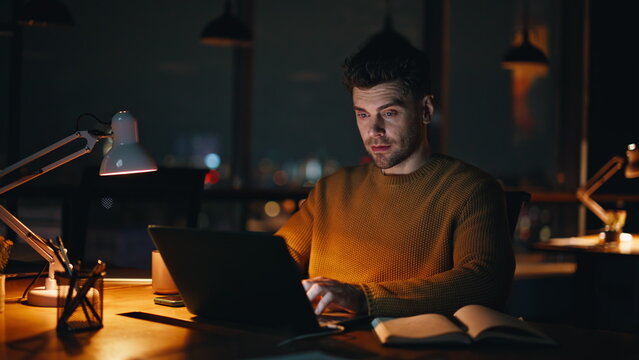 Freelancer programming laptop late evening in coworking office serious closeup. 