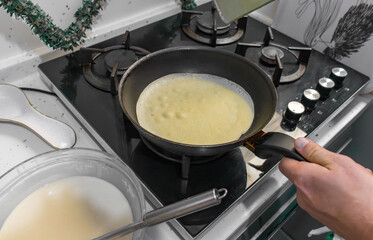 Pancakes are fried in a hot pan. Traditional homemade baking and cooking process.A series of home photos of the process of cooking pancakes in the kitchen. The pictures show different stages of the