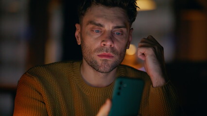 Overtime manager looking mobile phone sitting dark office space alone closeup. 