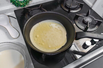 Pancakes are fried in a hot pan. Traditional homemade baking and cooking process.A series of home photos of the process of cooking pancakes in the kitchen. The pictures show different stages of the