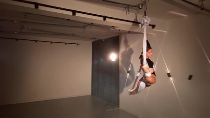 Young woman spinning in an aerial hammock in a studio