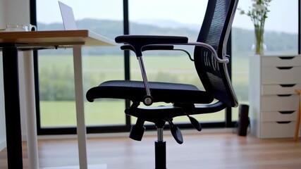 Black mesh office chair next to a light wood desk