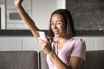 Digital victory. Excited lucky gen z girl celebrate unexpected virtual win scream with joy raise hand up looking at cellphone screen get prize notification crypto gain reward message great news text