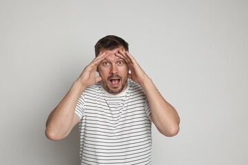 Man suffering from panic attack on light grey background