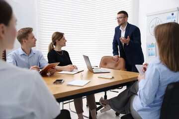 Business coach giving presentation to group of people in office