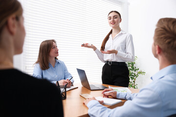 Business coach giving presentation to group of people in office