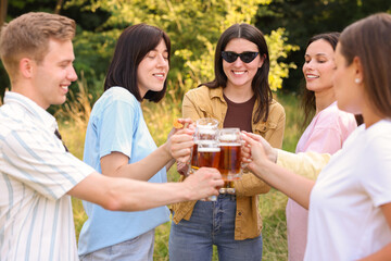 Group of happy friends clinking glasses of beer outdoors