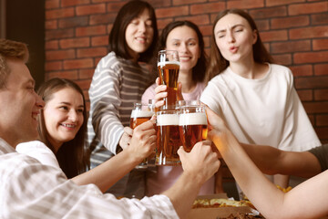Group of happy friends clinking glasses of beer at table indoors, selective focus