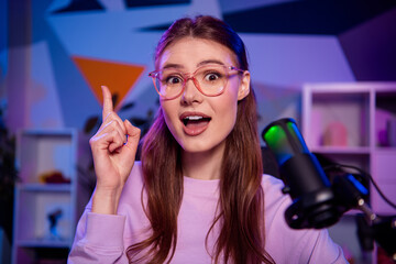 Young woman podcasting with vibrant neon lights, expressing ideas and engaging thoughts in a modern...