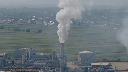 Lumber factory emitting smoke from chimney in rural landscape