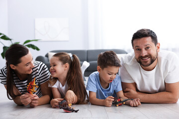 Parents and their kids playing with toys on warm floor at home. Heating system
