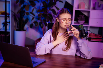 Young woman podcasting from home in a casual setup with neon lighting