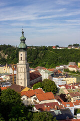 Church tower with green dome roof and clock in Burghausen, Bavaria, Germany, overlooking the river and colorful old town houses, photographed in 2024.