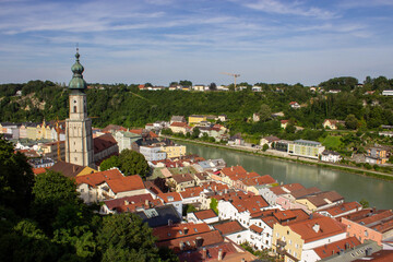 Church tower with green dome roof and clock in Burghausen, Bavaria, Germany, overlooking the river and colorful old town houses, photographed in 2024.
