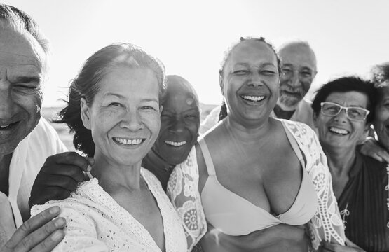 Happy senior people having fun on the beach at sunset time while wearing summer clothes - Joyful elderly lifestyle, vacation and travel concept - Focus on asian woman face - Black and white editing