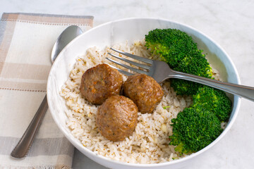 three meat balls served with rice and broccoli