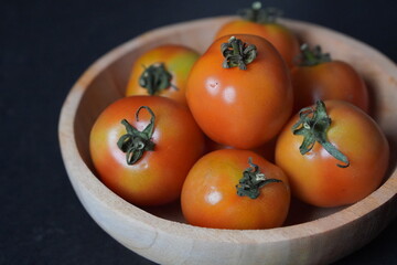 Fresh Tomatoes in Wooden Bowl on Dark Background