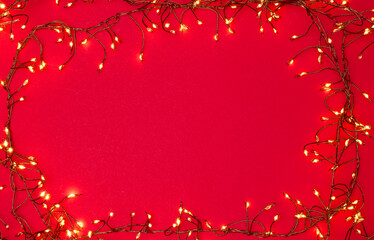 Christmas string lights glowing on red background, festive holiday garland decoration, top view...